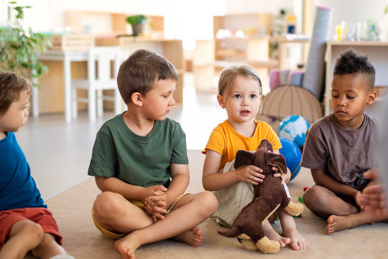 Kindergartenkinder sitzen auf dem Boden und hören zu.